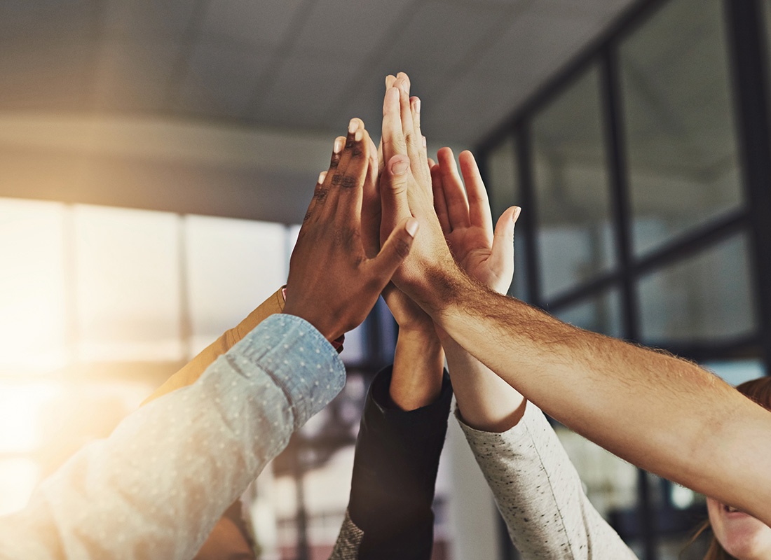 About Our Agency - Close Up of Business Team Members Sharing a High Five in a Group Huddle in a Modern Office