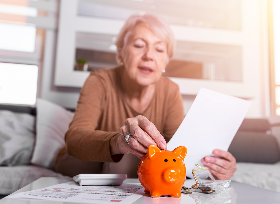 Annuities - Senior Woman Looking Over Retirement Information with a Piggy Bank